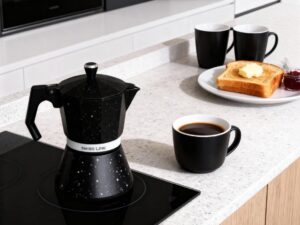 Cafetera en una encimera junto con tazas y un desayuno